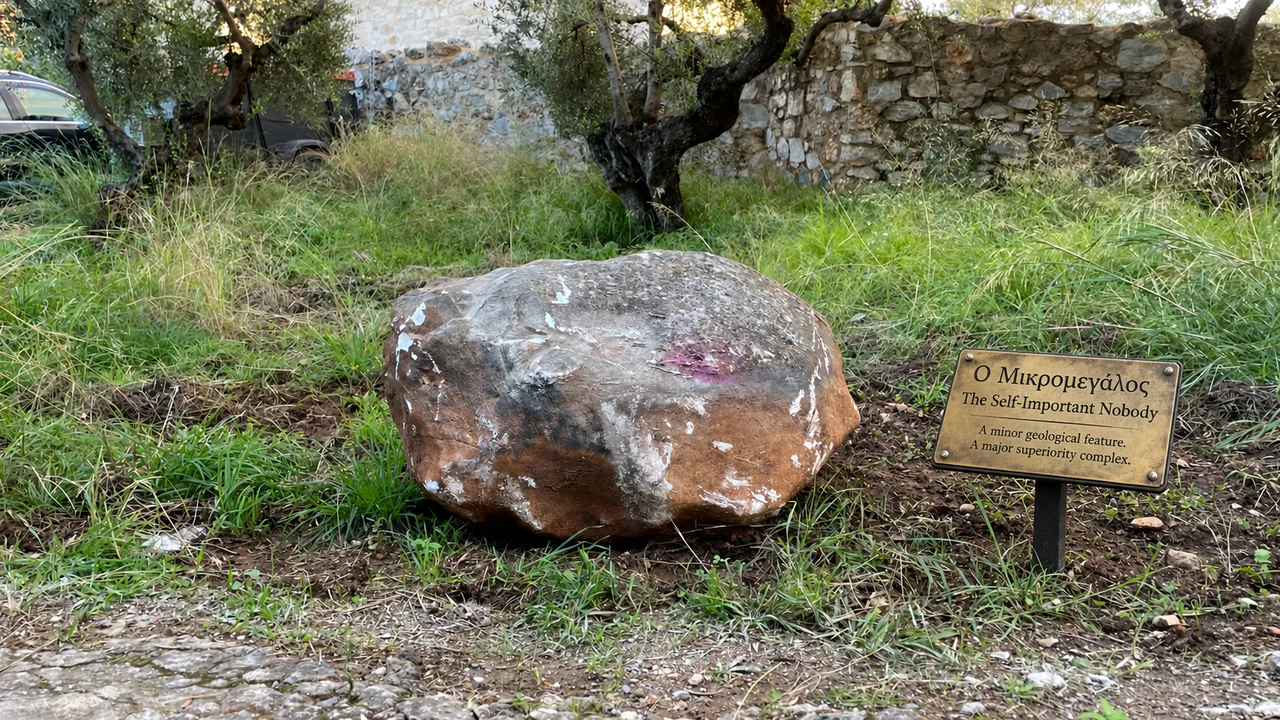 Συμπαγής πέτρα με λευκές γραμμές, με ψηφιακά προστιθέμενη μουσειακή πινακίδα